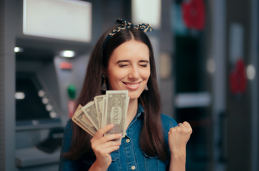 Girl having financial success holding dollars in front of a bank